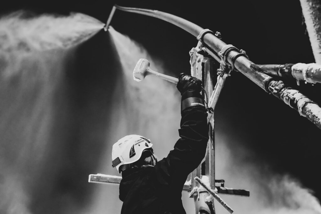 black and white image of someone working on a snow-making machine using a mallet