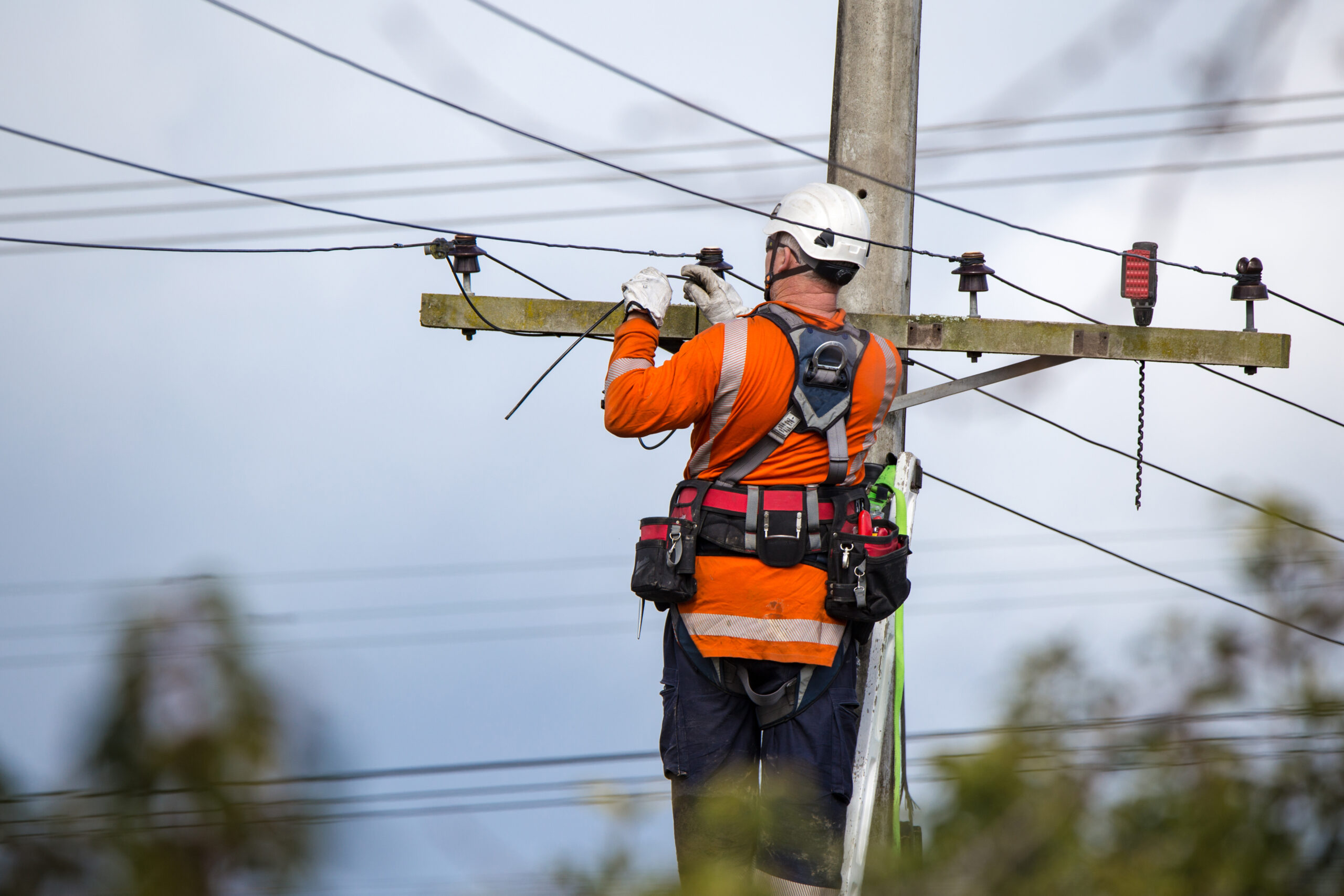 A linesman with a power company connects a new house in a rural