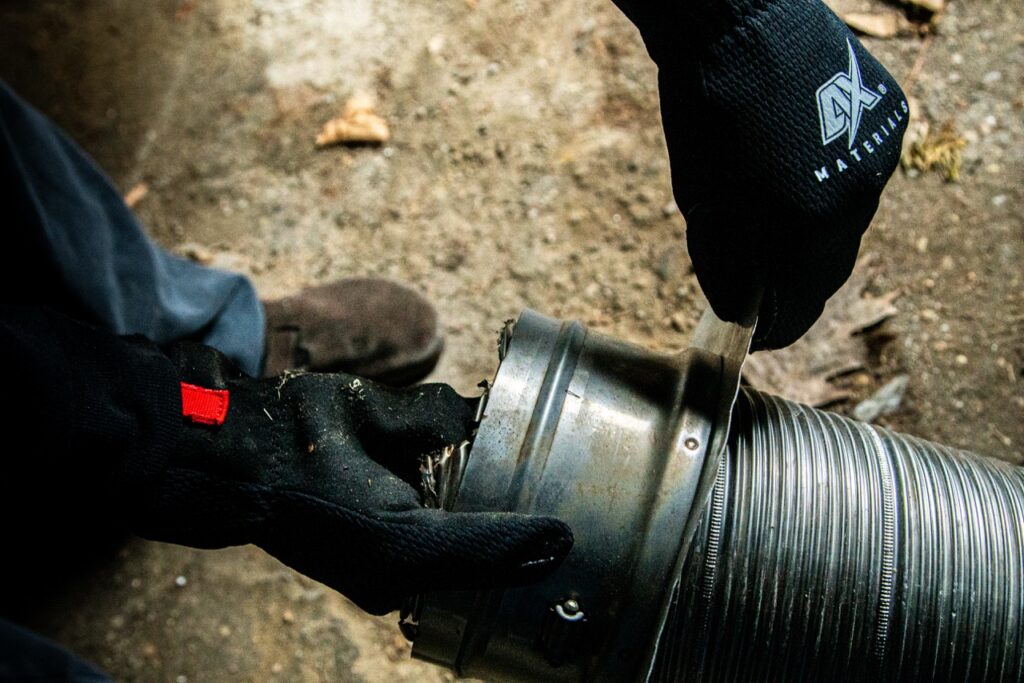 Close-up of hands wearing gloves, repairing a metal pipe.