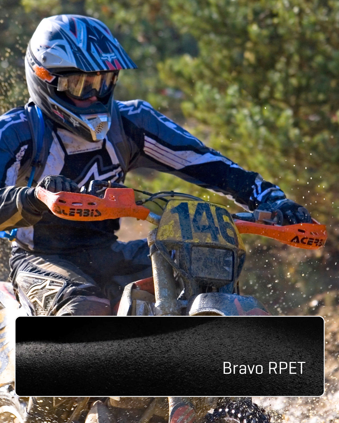 A motocross rider wearing protective gear and gloves racing on a dirt bike in a wooded area.